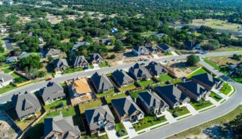 Aerial drone view above suburb homes curved road into suburban community