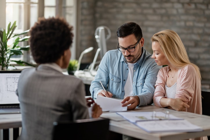 Couple signing a contract on a meeting with real estate agent.