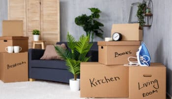 Moving to new house - brown cardboard boxes with belongings stacked in living room after moving day
